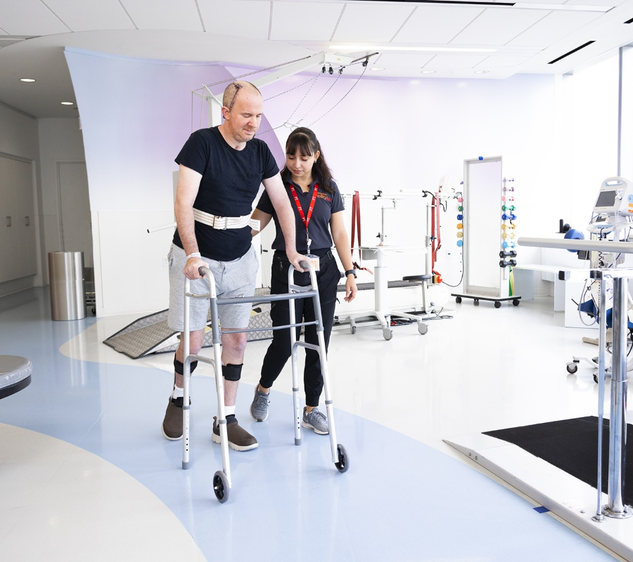 Patient rebuilding strength and mobility during post-ICU rehabilitation with physiotherapist support